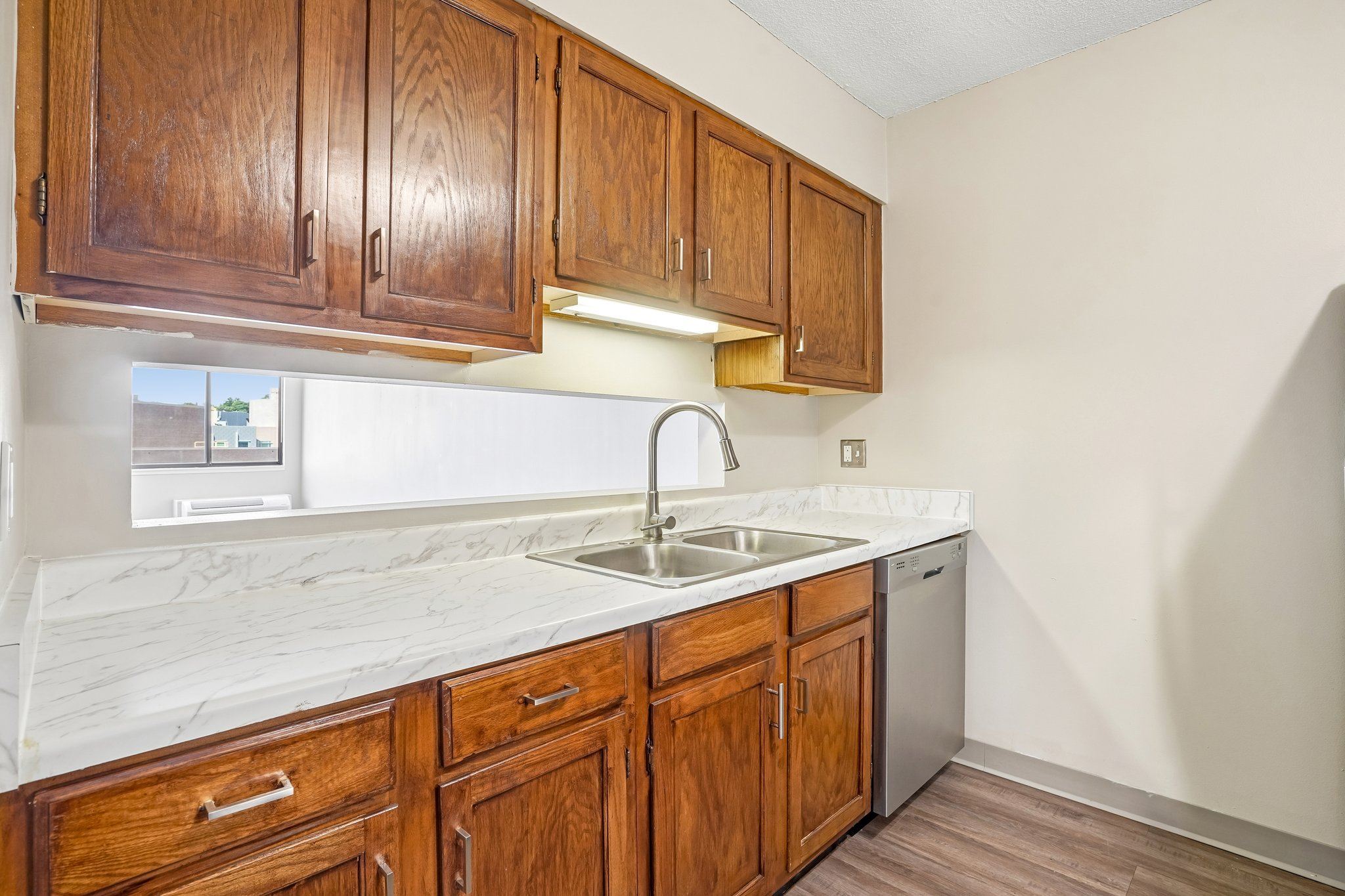 Irvine Park Towers kitchen with wood cabinets, light countertops, sink and dishwasher